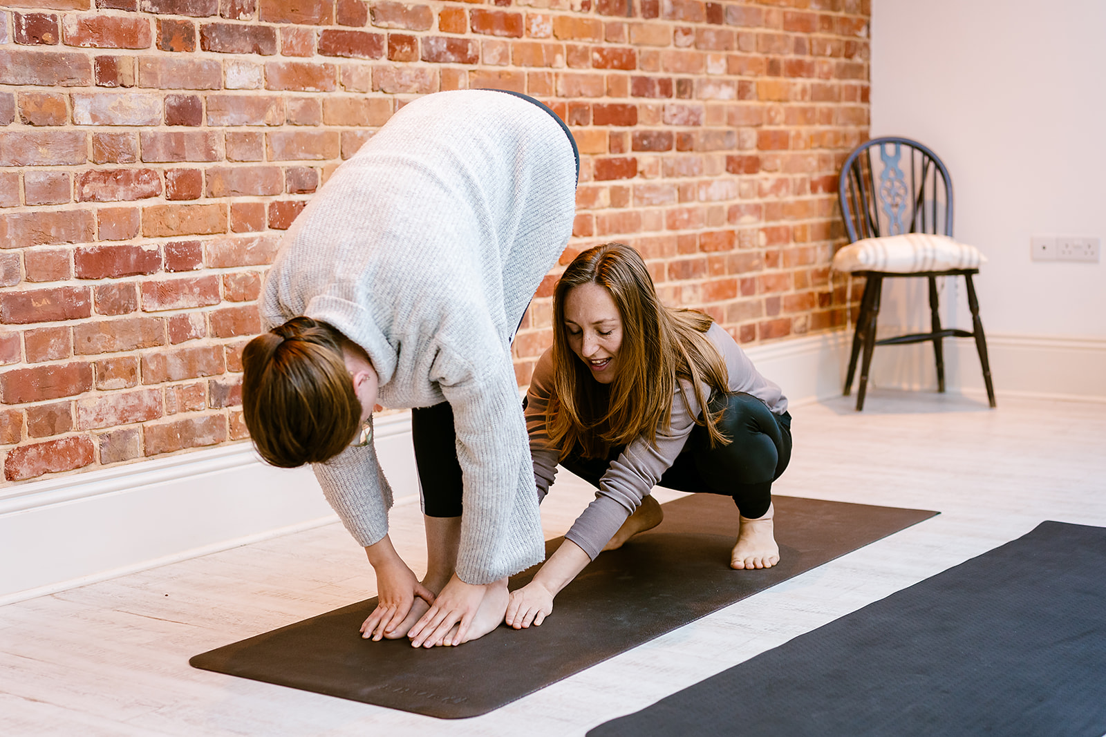 Yoga teaching with a woman touching her toes, and Lucy helping.